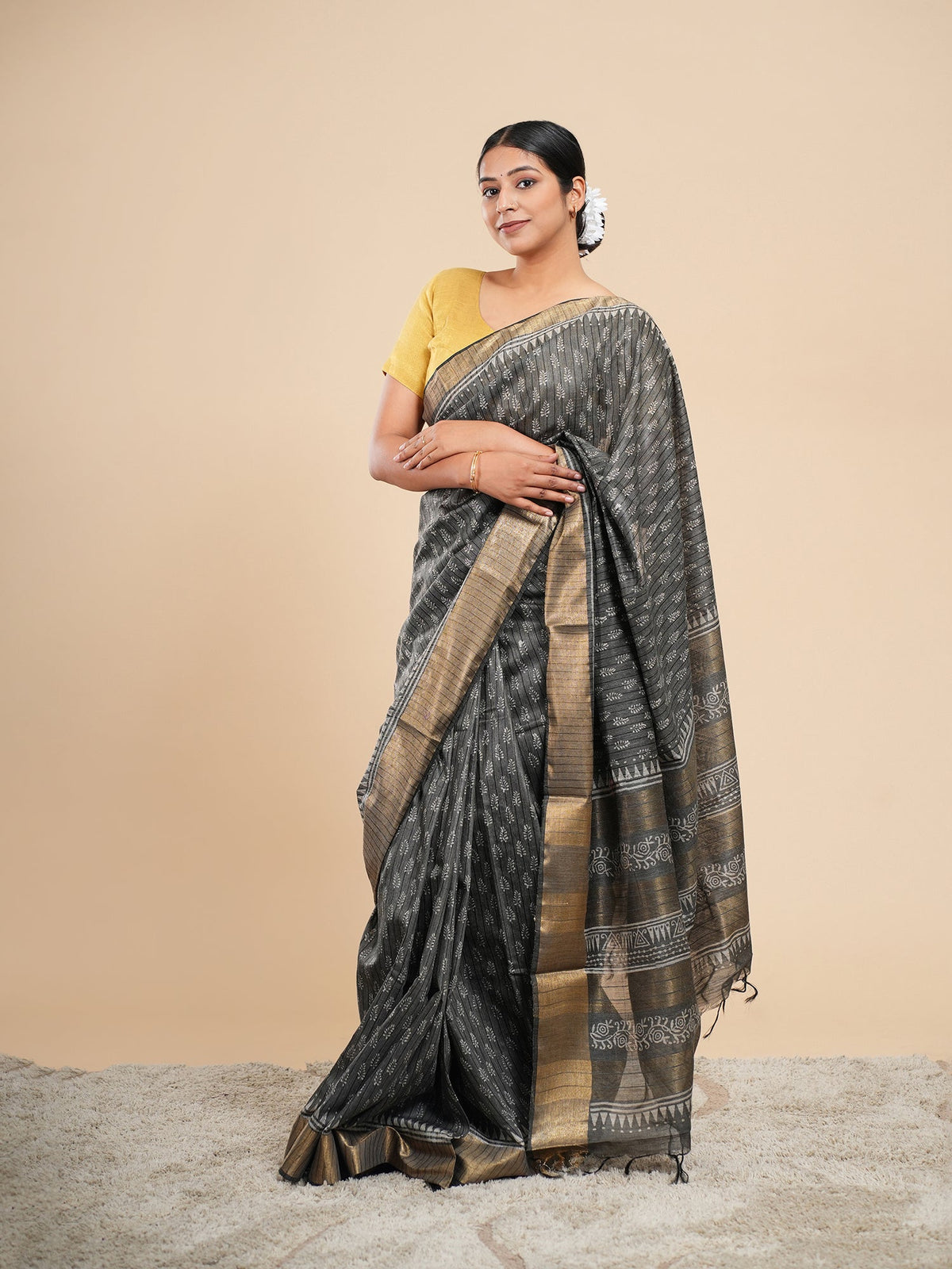 Charcoal grey bamboo silk saree draped for office wear, showing the soft fall and antique gold zari border — Koshnika